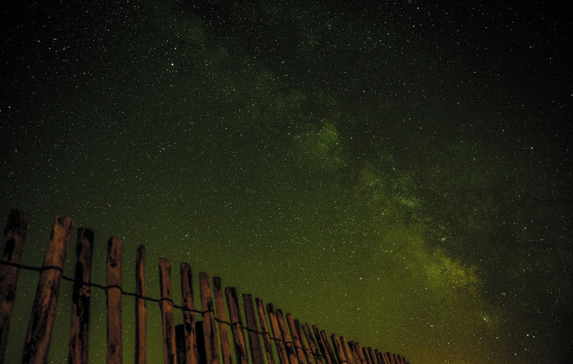 Photograph of a wooden fence against a star-filled night sky