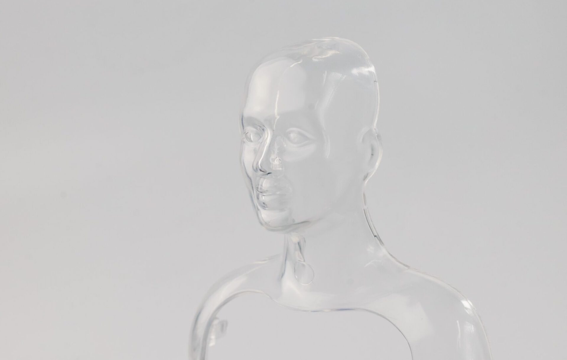 Image of a clear plastic mould of a human face and shoulders, on a white background.