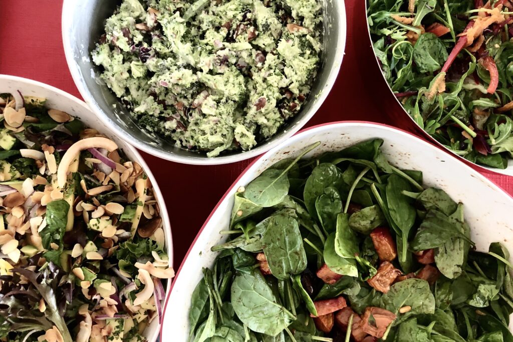 A selection of colourful salads in bowls on a red tablecloth.